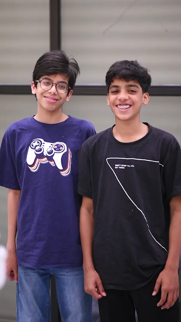Two smiling teenage boys at Smile Mender, Gujranwala, one wearing metal braces