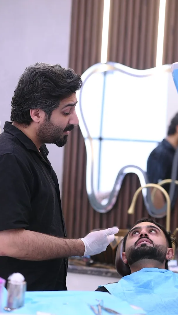Dentist talking with a patient in the dental chair, in front of a tooth-shaped mirror at Smile Mender, Gujranwala